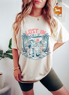 "Lost in Paradise Oversized TShirt, Comfort Colors Summer Shirt, Graphic Tees For Women, Boho Tee, Summer Vibes Shirt, Retro Vacation Shirt Whether you're hitting the road for a cross-country adventure or just hanging out with friends, you'll love its comfortable, oversized fit with this Comfort Colors shirt. The mineral wash feel is super soft and perfect for any casual occasion. Rock this tee with your favorite jeans or leggings and you'll look great no matter what. This is a standard unisex size Comfort Colors Tee. For an oversized tee, please size up. If you are looking for an oversized \"T-shirt Dress\" look, we recommend sizing up 2 sizes. Please review the size chart to ensure you receive the fit you want. HOW TO ORDER 1- Select \"Shirt Size\". 2- Select quantity. 3- Click \"Add To Country Concert Outfits, Cottagecore Fall, Comfort Colors Tshirt, Shirt Graphics, Cowgirl Shirts, Skeleton Shirt, Kill Bill, Country Shirts, Concert Shirts