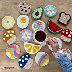 a person is holding a coffee cup in front of some crocheted coasters