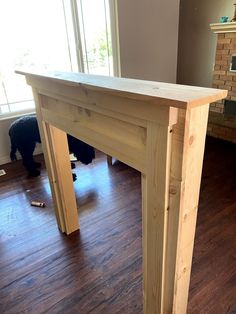 a wooden table sitting on top of a hard wood floor next to a fire place