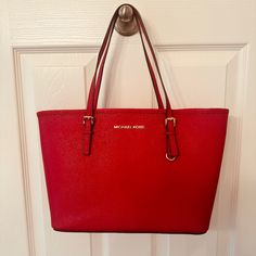 This Is A Classic Michael Kors Red Jet Set Small Travel Tote. It Measures 9" High With A Flat Structured Base Of 5.25" X 11". The Tote Sides Are 15" At The Top That Tapers To 11" At The Base. It Is Red Saffiano Leather With Brass Accents Including A Leather Fob And An Interior Key Leash (9.5" Long). The Interior Also Has A Front Slip Pocket And A Back Zip Pocket. There Is A Brass Swivel Eye Snap Hook (See Photo) At The Top To Close The Tote. Included Is A Mk Dust Bag. It Comes From A Pet Free An Classic Red Shoulder Bag For Errands, Classic Red Bag With Branded Hardware, Michael Kors Red Shoulder Bag For Daily Use, Michael Kors Red Bag For Everyday Use, Michael Kors Red Bag With Handles, Red Michael Kors Shoulder Bag For Daily Use, Red Michael Kors Bag With Handles, Classic Red Shopping Bag, Michael Kors Red Rectangular Shoulder Bag