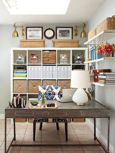 a home office with lots of shelves and baskets on the wall, along with a desk