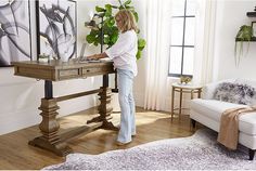 a woman is standing at a desk in her living room