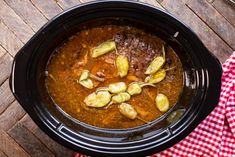 a stew in a crock pot on a wooden table