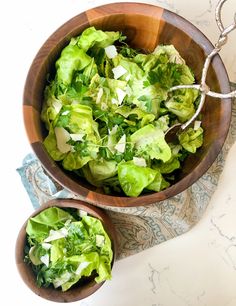 two wooden bowls filled with lettuce on top of a table