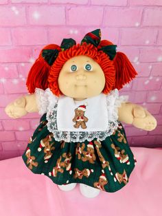 a doll with red hair wearing a green dress and gingerbreads on it's chest