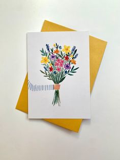 a bouquet of flowers is on top of two yellow and white greeting cards, both with matching envelopes