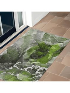 a green area rug sitting on top of a tile floor next to a door way