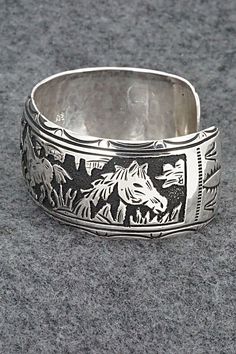 This expertly crafted sterling silver bracelet featuring horses was made by Navajo silversmith Richard Singer. The back is signed R Singer and stamped .925.Size: 5 5/8" (will fit up to a 6 3/4" wrist)Gap: 1 1/8"Width: 1"Free shipping on all orders! We ship with USPS and always include tracking. All orders ship within a day of payment.Returns are accepted up to 30 days after you receive your order. Just send us a message. Our shop offers cash back or store credit. The item must be returned in new Sterling Silver Southwestern Bracelet With Polished Finish, Silver Hand Tooled Bracelet For Gift, Handcrafted Silver Bracelets As Gift, Hand Tooled Silver Bracelet As A Gift, Hand Tooled Silver Bracelets As A Gift, Hand Tooled Silver Bracelet For Gift, Collectible Western Style Bangle, Southwestern Silver Cuff Bracelet With Inlay, Adjustable Etched Southwestern Sterling Silver Bracelet