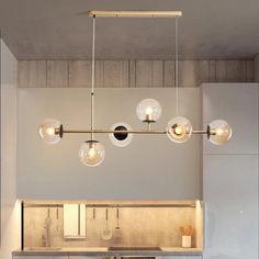 a kitchen area with a sink, counter and lights hanging from the ceiling above it