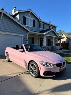 a pink bmw convertible parked in front of a house