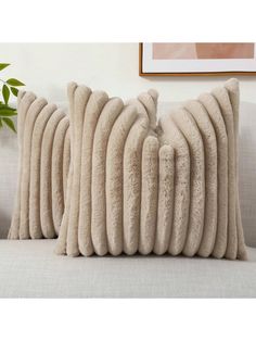 two beige pillows sitting on top of a couch