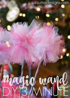 two pink tulle flowers in front of a christmas tree with lights on the background