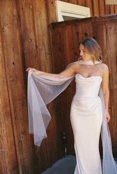 a woman in a white dress is holding a veil