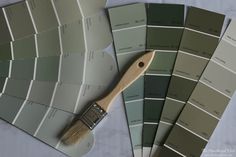 some paint samples and a brush sitting on top of each other in shades of green