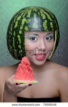 a woman with a watermelon helmet on her head holding a piece of fruit