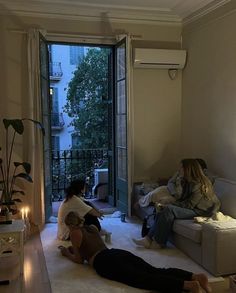 two women sitting on the floor in front of a sliding glass door, while another woman lays on the floor