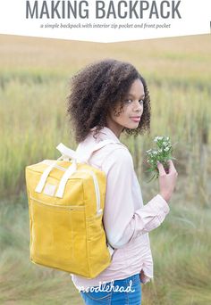 a woman with a yellow backpack and flowers in her hand is looking at the camera