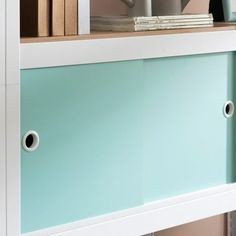 a book shelf with some books on top of it and a cup in the middle