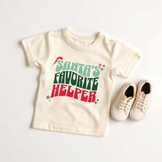 "Kids will look adorable in this \"SANTA'S FAVORITE HELPER\" youth short sleeve tee. This lightweight side-seamed shirt maximizes comfort all day long.  Santa's Favorite Helper Kids Toddler Youth, Christmas T Shirt, Santa Shirts for Kids, Boy Kids Holiday Outfit Holiday Shirts 🌟100% Airlume combed and ringspun cotton (fiber content may vary for different colors) 🌟Light fabric (3.9 oz/yd² (132 g/m 🌟Retail fit RETURNS: All products are made-to-order and because of the nature of these items, all Pre-shrunk Short Sleeve Christmas Tops, White Short Sleeve Christmas Shirt, Christmas Cotton Short Sleeve Shirt, Family Matching Short Sleeve Holiday Shirt, Family Matching Holiday Tops With Short Sleeves, Cute Short Sleeve T-shirt For Winter, Cute Christmas T-shirt With Letter Print, Festive Holiday Short Sleeve T-shirt, Festive Short Sleeve Shirt With Letter Print