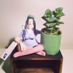 a small figurine sitting next to a potted plant on top of a table