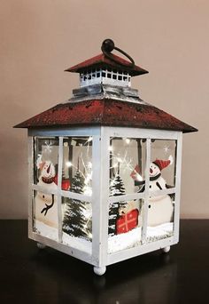 a lantern with snowmen and christmas trees in it