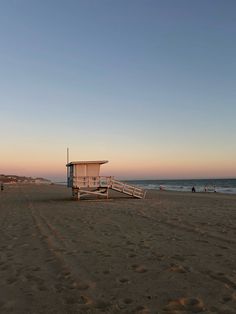 a lifeguard station on the beach at sunset