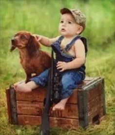 a little boy sitting on top of a wooden crate next to a dog