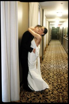 a bride and groom are hugging in the hallway