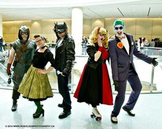 group of people dressed up as batman and catwomans in an airport lobby, posing for the camera