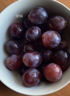 a white bowl filled with grapes on top of a wooden table