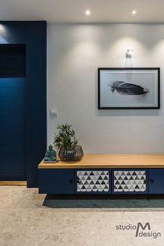 a living room with blue furniture and artwork on the wall, along with potted plants