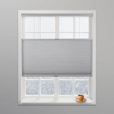 a white window with blinds in it and a cup on the ledge next to it