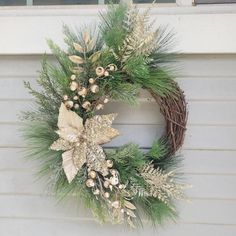 a christmas wreath hanging on the side of a house with pine cones and greenery