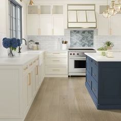 a kitchen with white cabinets and blue island in the center, along with wooden floors