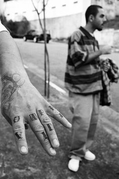 a man standing on the street with his hand in front of him that has tattoos on it