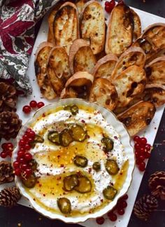 a platter filled with bread, pickles and dip surrounded by other appetizers