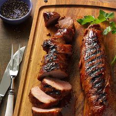 sliced pork on a cutting board with garnishes and seasoning next to it