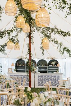 tables and chairs are set up in a tent for an outdoor wedding reception with hanging lights