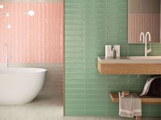 a bathroom with green and pink tiles on the walls, a bathtub and sink