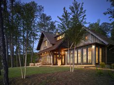 a large house with lots of windows and trees in the front yard at night time