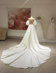 a wedding dress on display in a bridal room with other gowns behind it