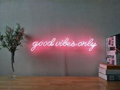 a pink neon sign that says dreaming next to some books and a vase with flowers