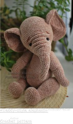 an elephant stuffed animal sitting on top of a table next to a potted plant