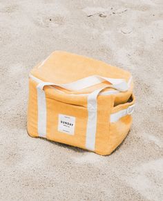 a yellow and white bag sitting in the sand