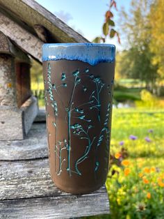 a brown and blue vase sitting on top of a wooden table