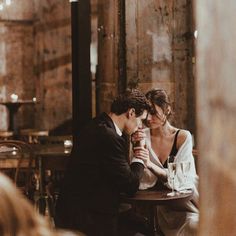 a man and woman sitting at a table in front of each other with wine glasses