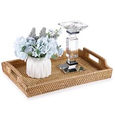 a wicker tray with flowers on it and a glass candle holder in the middle