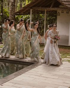 a group of women standing next to each other in front of a pool wearing sari