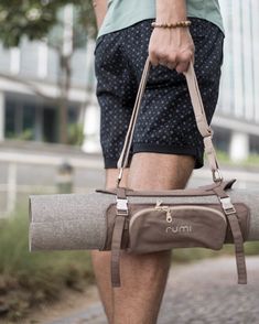 a man carrying a duffel bag while walking down the street with his legs crossed