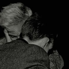 two people are hugging each other in the middle of black and white photo, with one person covering his face